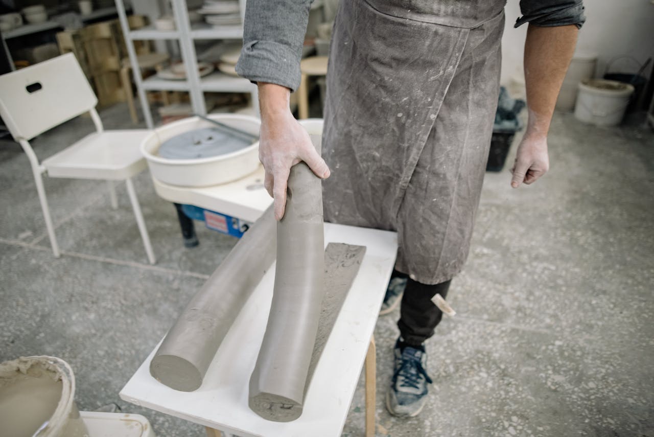 Artisan working with clay rolls in a creative workshop environment.
